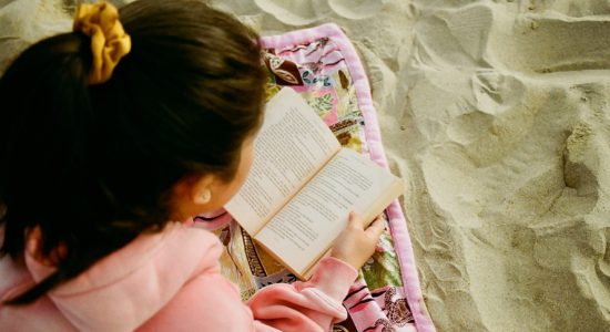 girl in pink hoodie reading book