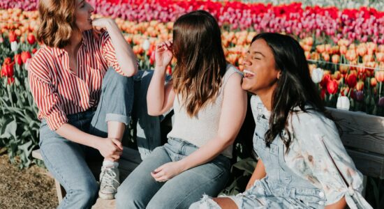 three women sitting wooden bench by the tulip flower field