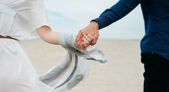 man and woman holding hands together in field during daytime