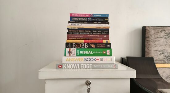 a stack of books sitting on top of a white dresser