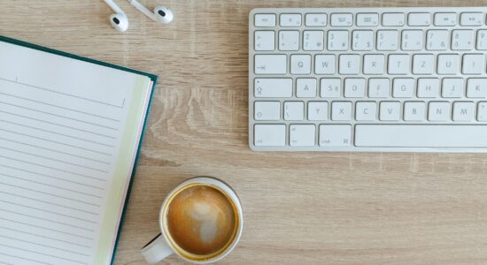 coffee latte near white wireless keyboard and Apple EarPods on the table photography